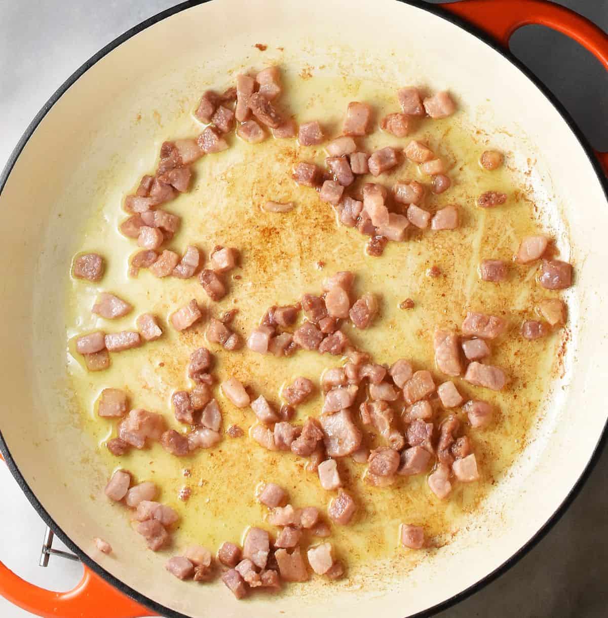 Fried cubes of pancetta in shallow pan.