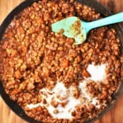 Thick lentil ragu sauce with cream in large shallow pan with blue spoon.