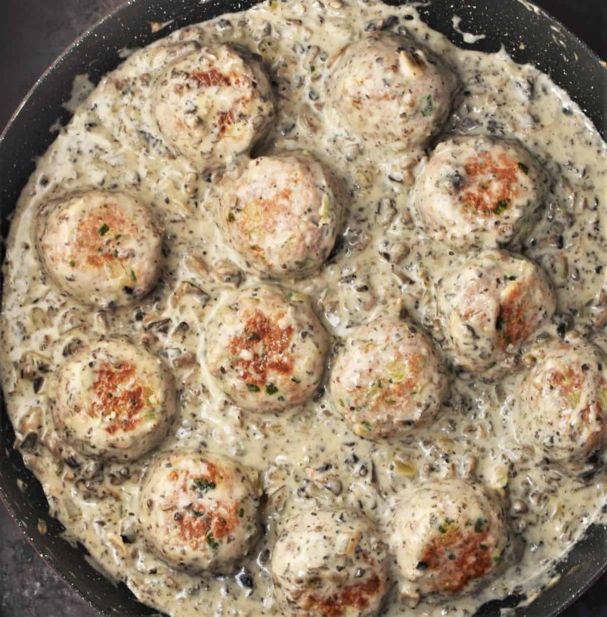 Meatballs in chunky mushroom sauce in large shallow pan.