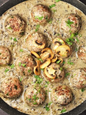 Top down view of meatballs in mushroom sauce in large pan.