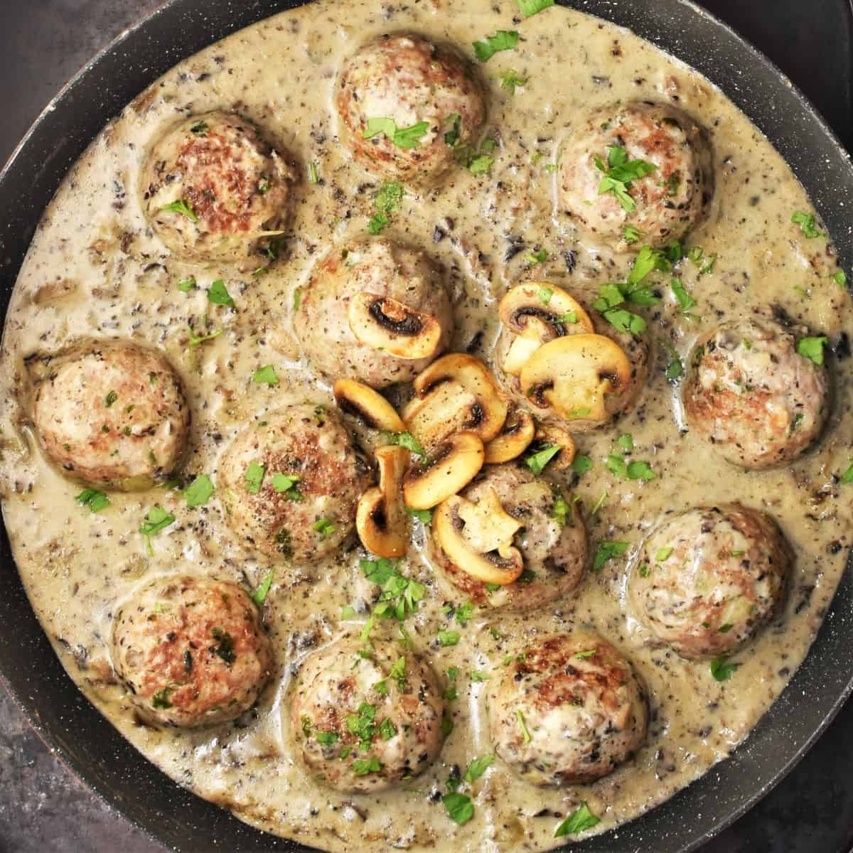 Top down view of meatballs in mushroom sauce in large pan.