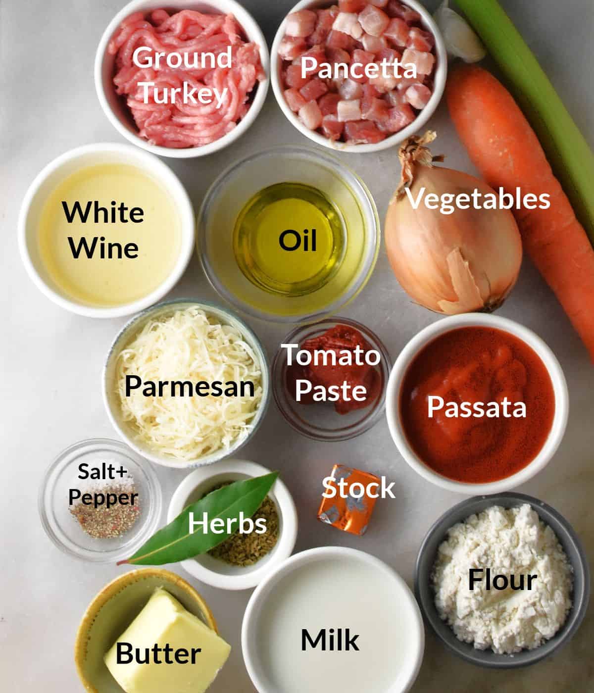 Top down view of turkey lasagna ingredients in individual dishes on marble top.
