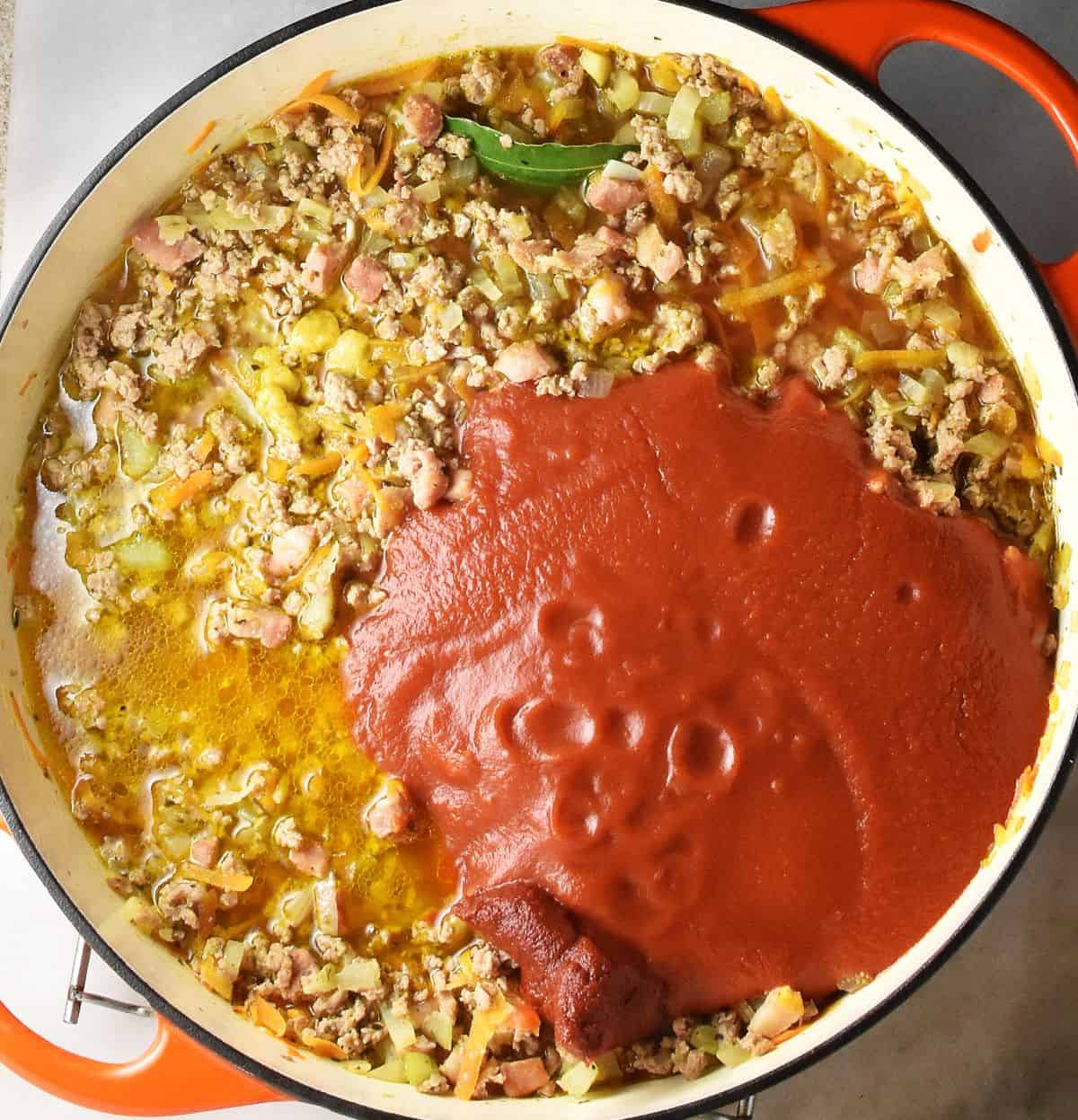 Ground turkey with vegetables and passata in large pan.