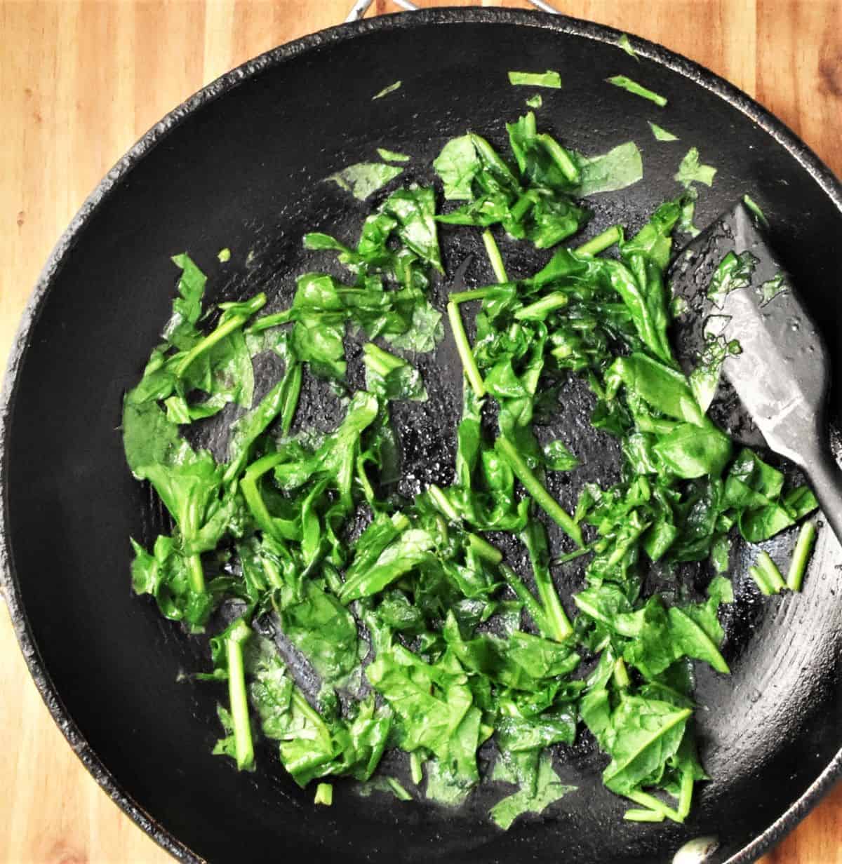 Wilted chopped spinach in pan.
