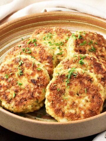 Side view of fried egg patties in brown bowl.