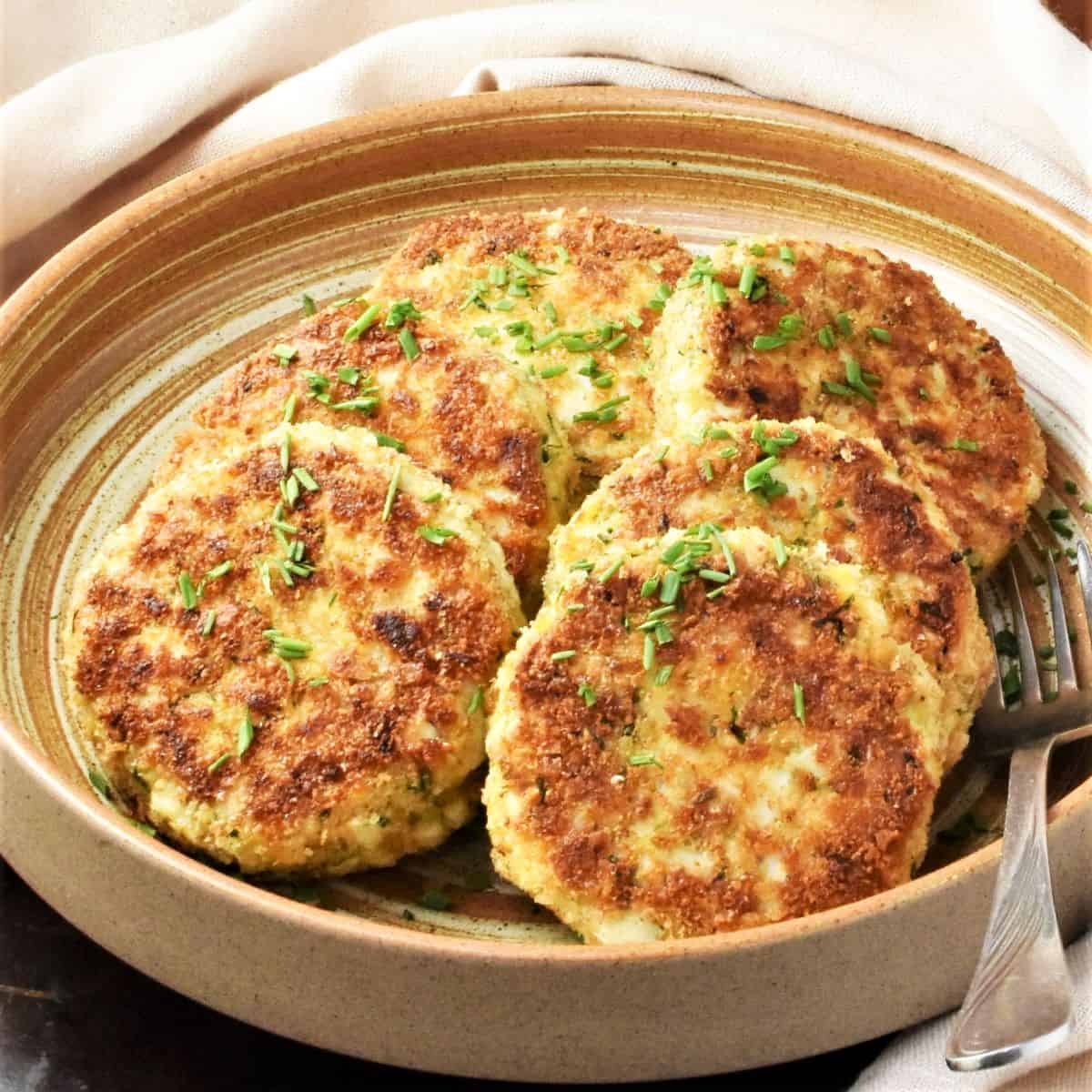 Side view of fried egg patties in brown bowl.