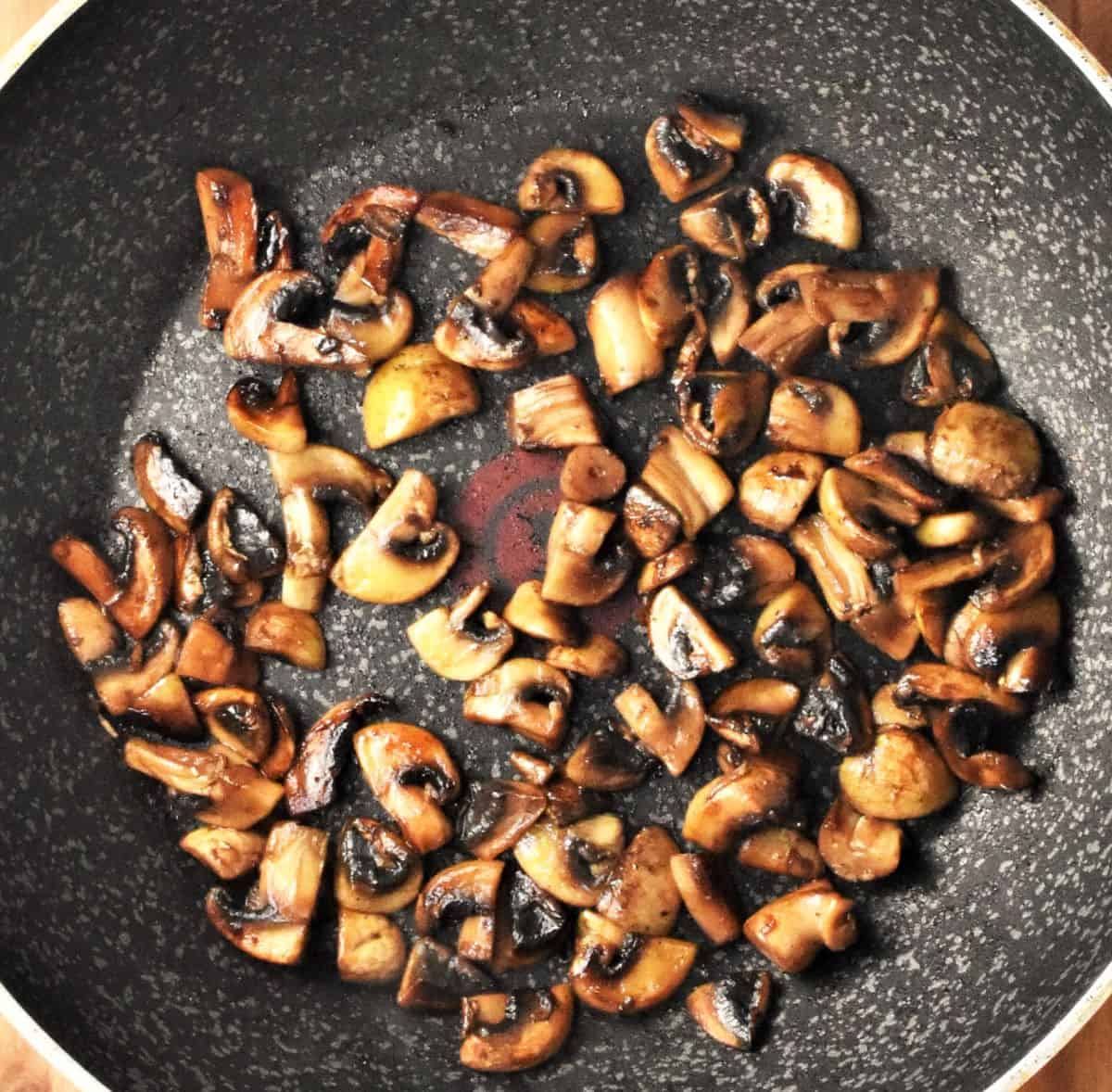 Cooking chopped mushrooms in pan.