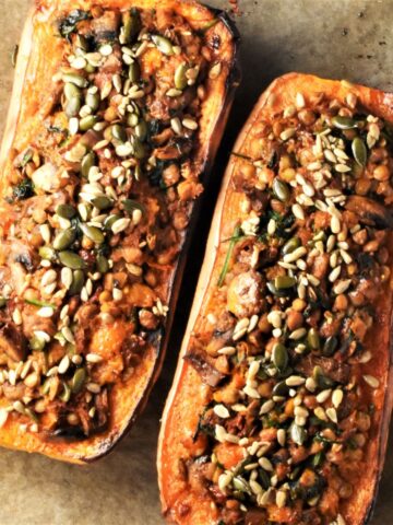 Top down view of 2 stuffed butternut squash halves on parchment.