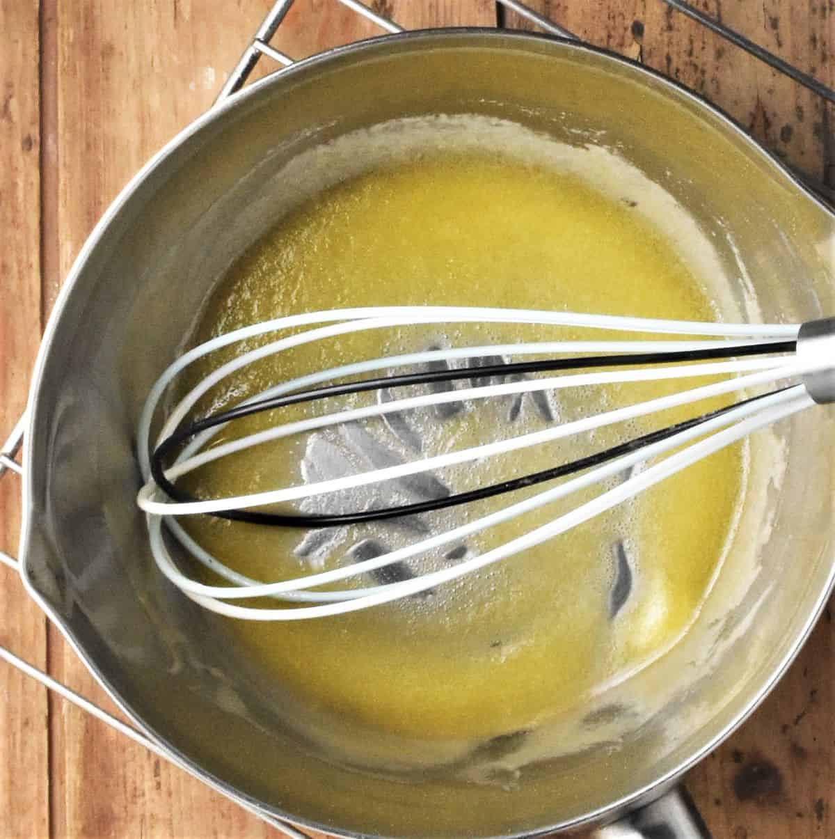 Making smooth roux mixture in pan with whisk.