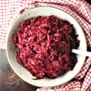 Top down view of Polish shredded beets in white bowl with spoon.