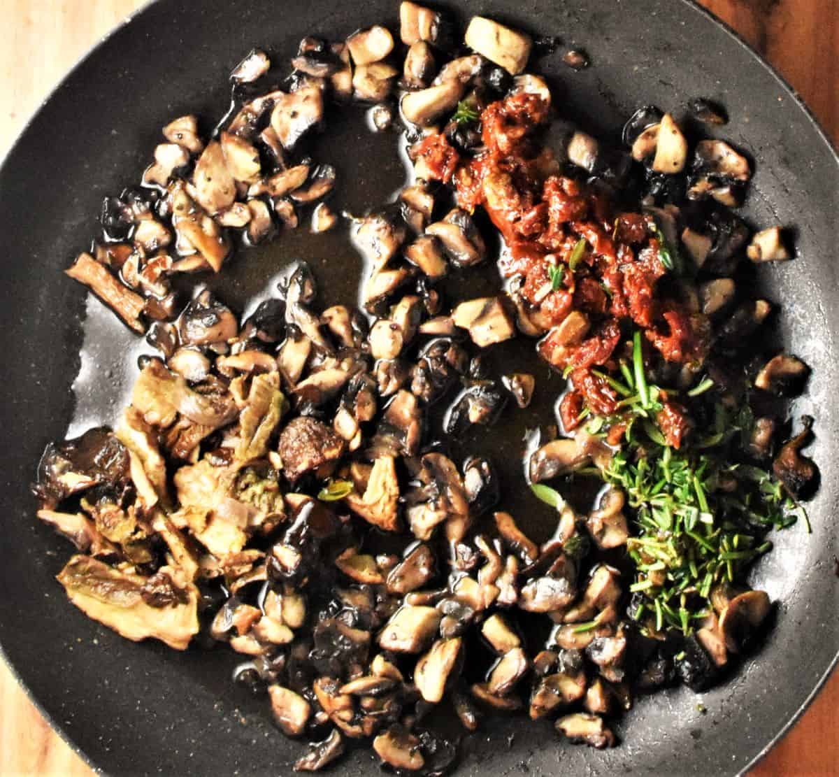 Chopped mushroom with herbs in frying pan.