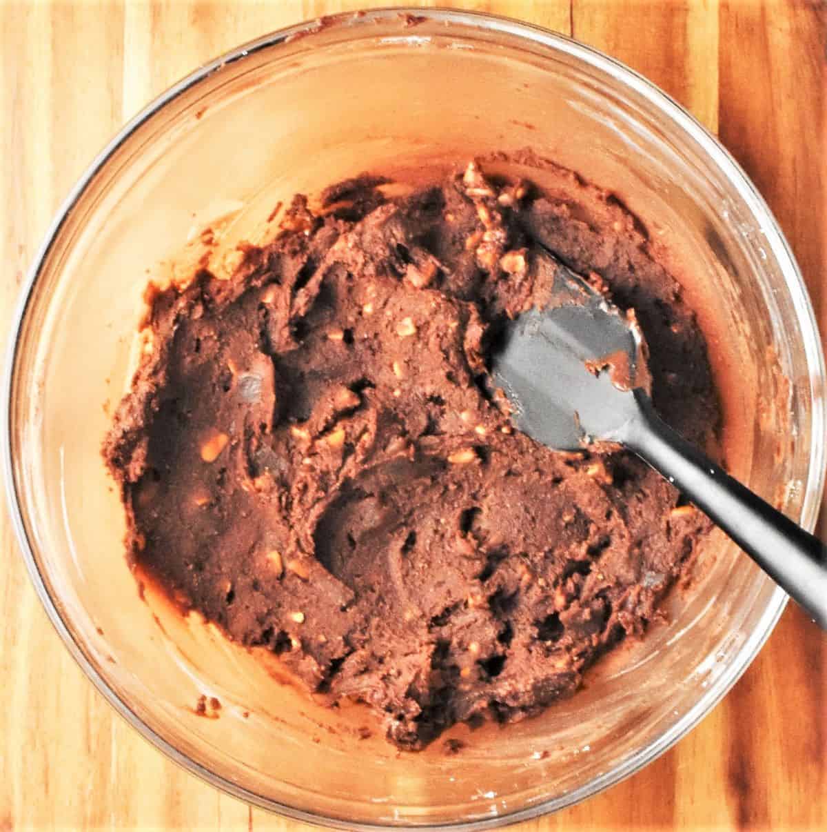 Chocolate and peanut butter truffle mixture in bowl with spatula.