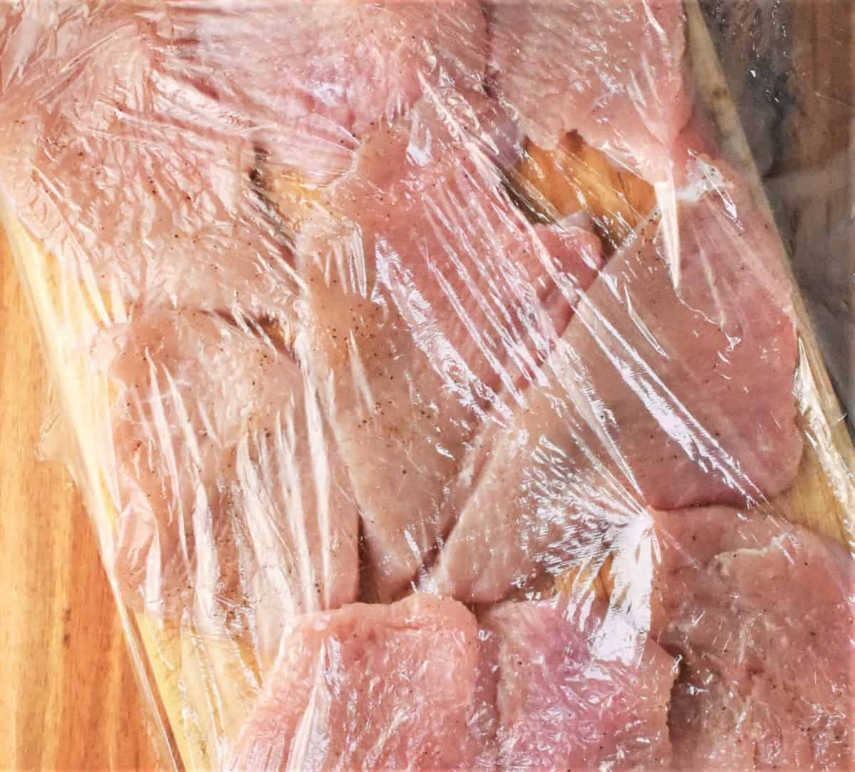Turkey breasts covered with plastic wrap.