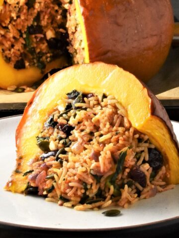 Side view of stuffed pumpkin slice on top of plate and pumpkin in background.