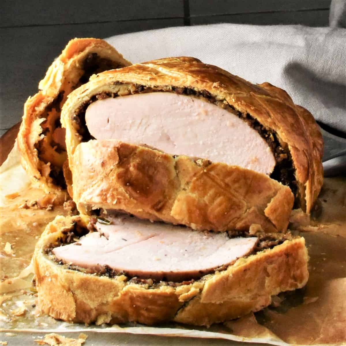 Side view of sliced turkey wellington on top of parchment.