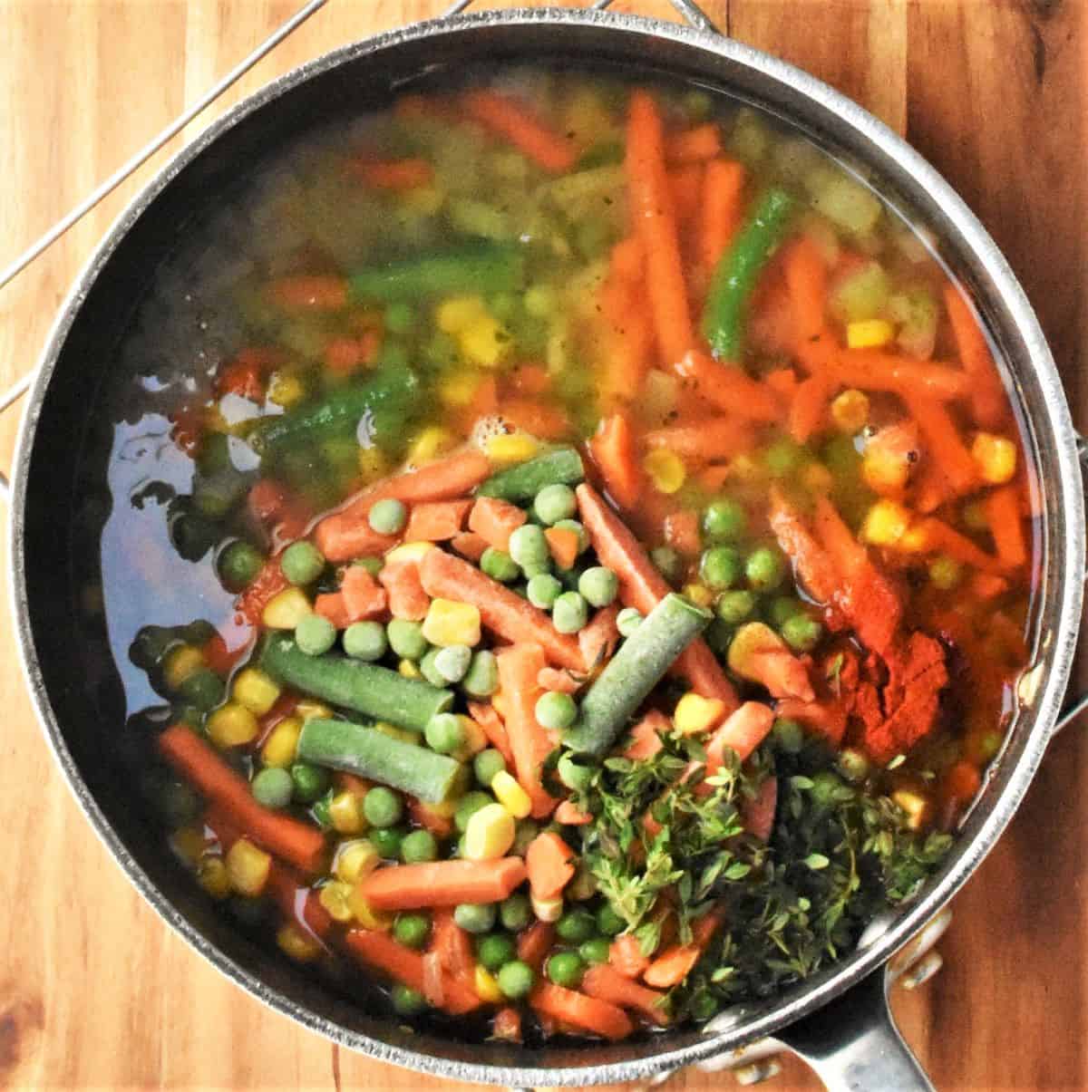 Top down view of soup with vegetables in pot.