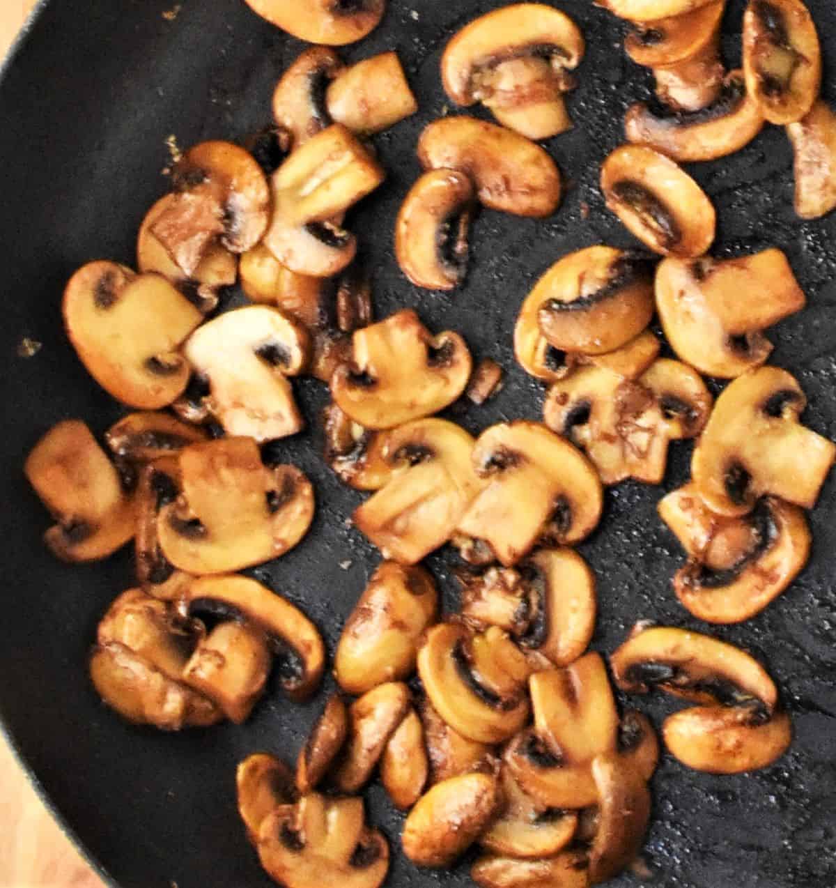 Top down view of sliced mushrooms in frying pan.