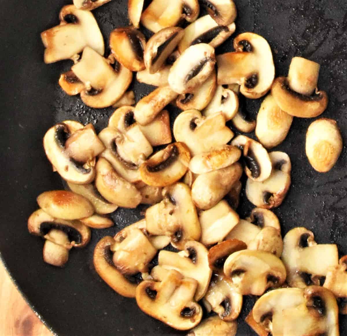 Slices of mushrooms in frying pan.