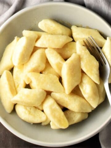 Top down view of pierogi dumplings in bowl with spoon.