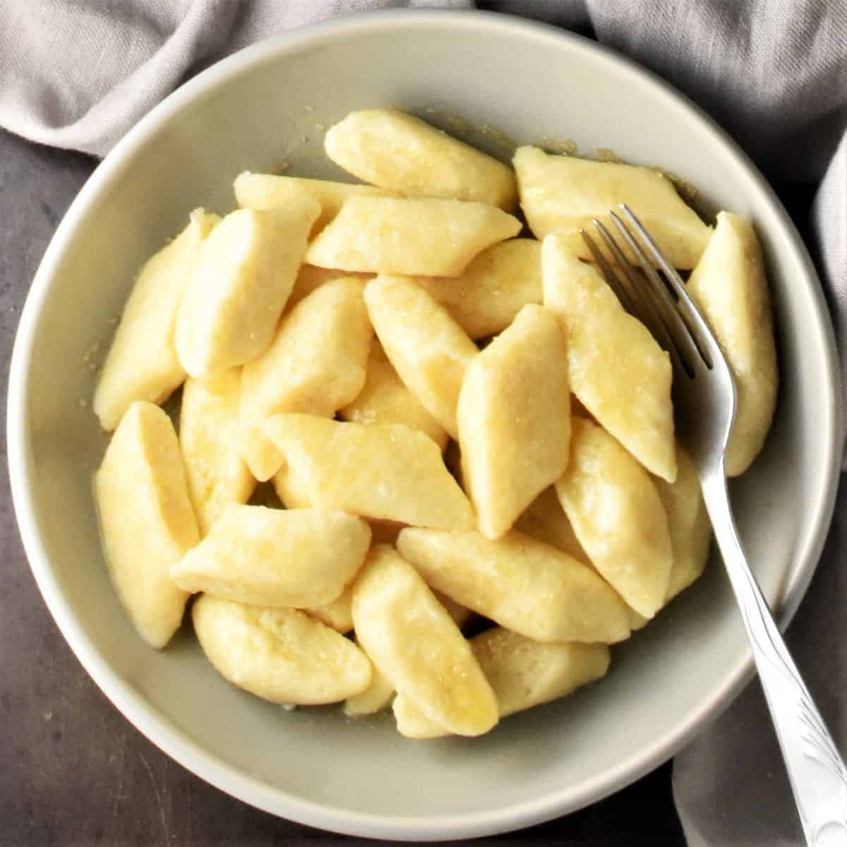 Top down view of pierogi dumplings in bowl with spoon.