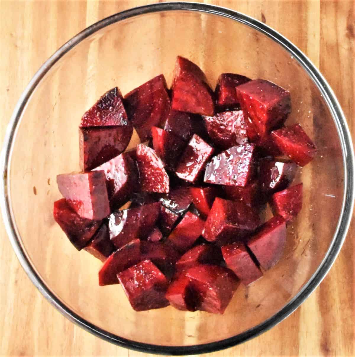 Top down view of beetroot pieces with oil in bowl.
