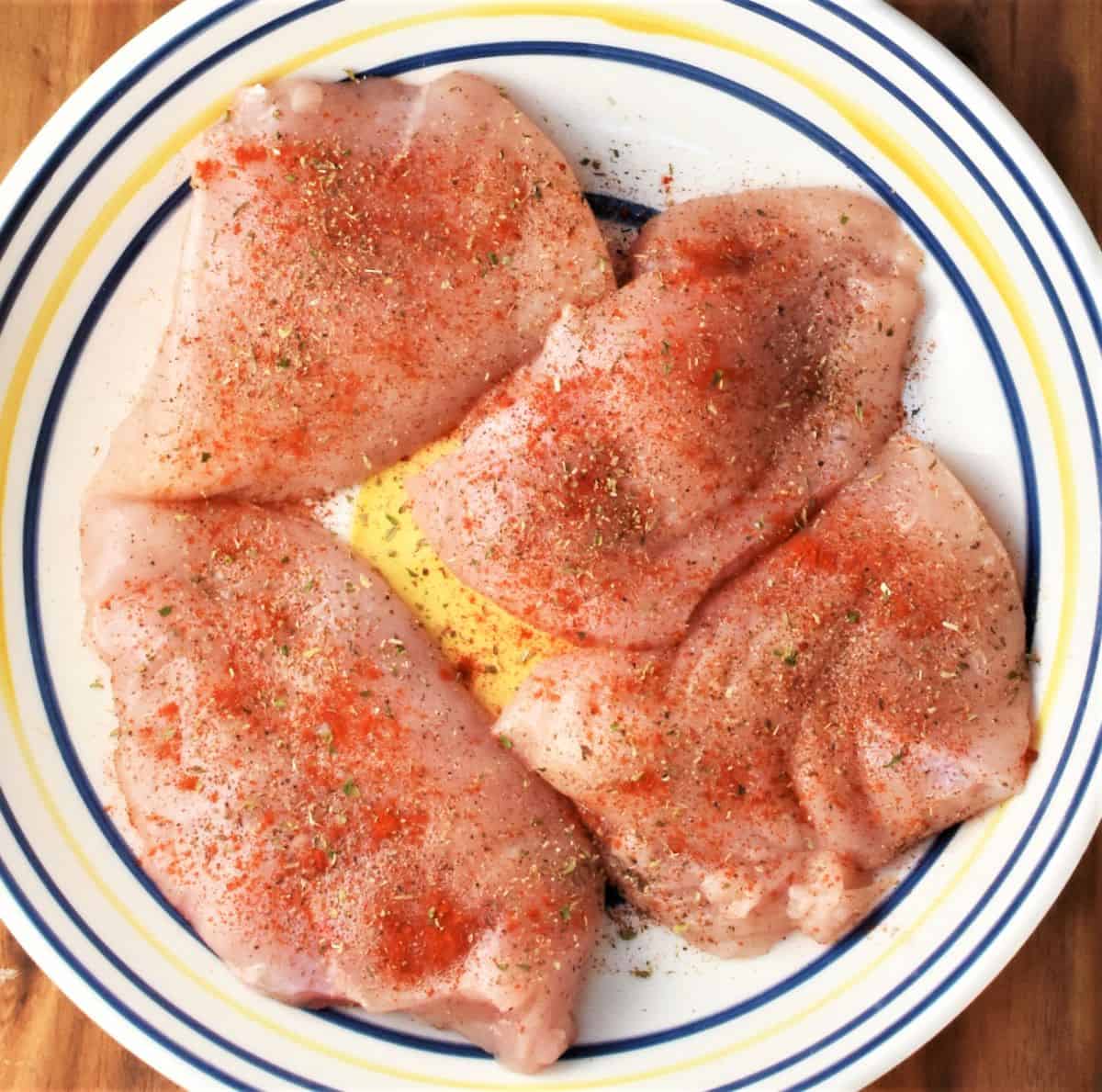 4 skinless chicken breasts  with seasoning in large bowl.