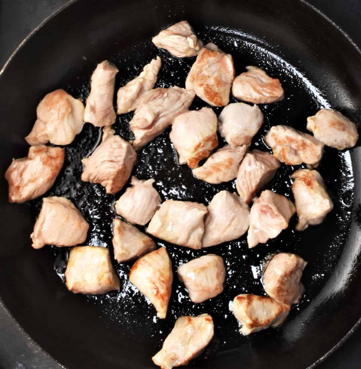 Browning chunks of pork in pan.