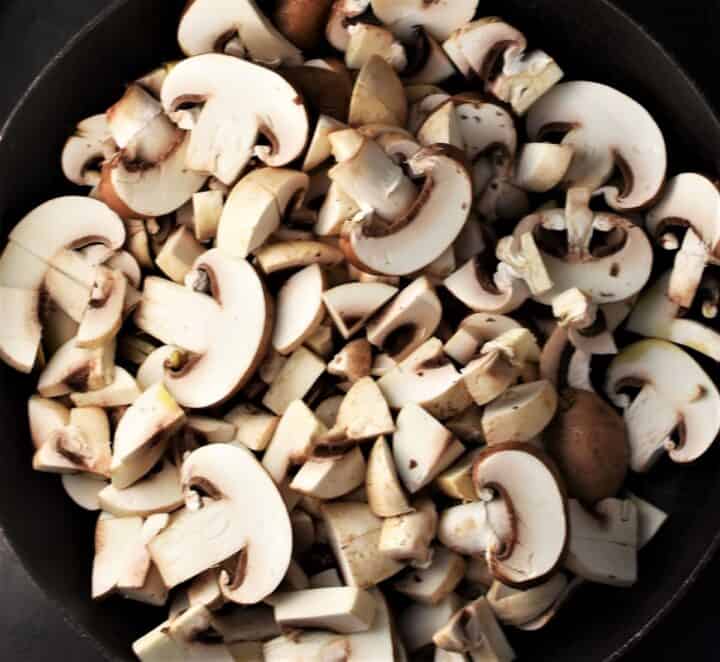 Top down view of sliced and chopped mushroom in large pan.