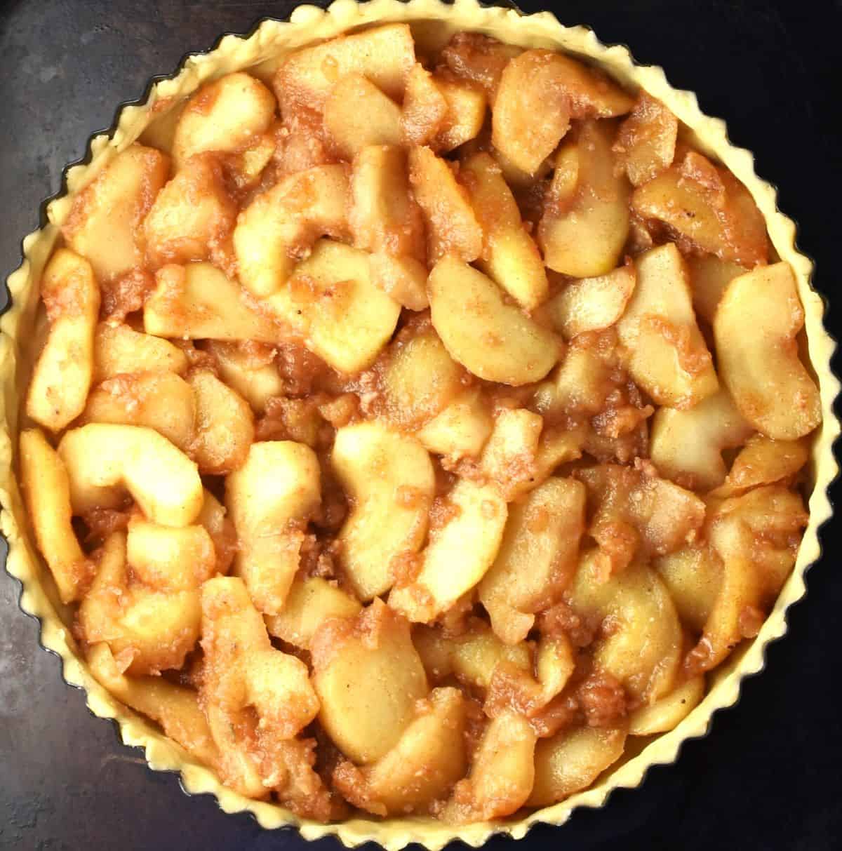 Apple slices in tart pan with pastry.