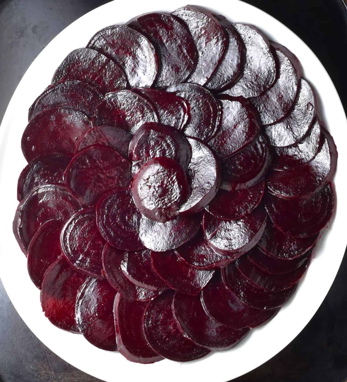 Sliced beets arranged in single layer on white plate.