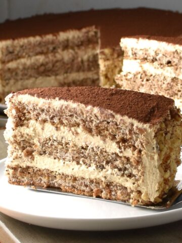 Side view of Polish walnut cake slice on white plate.