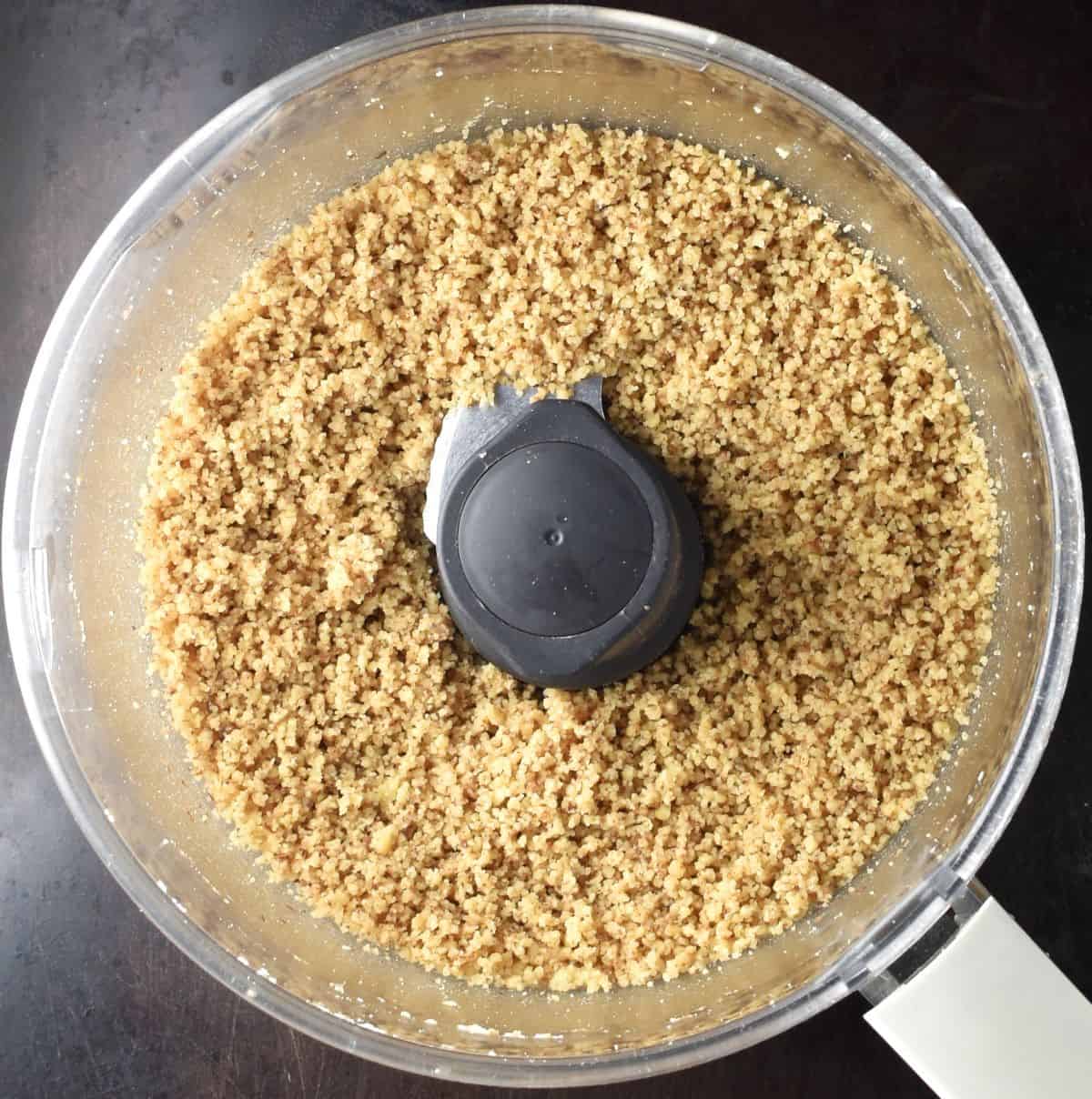Top down view of ground walnuts in food processor.