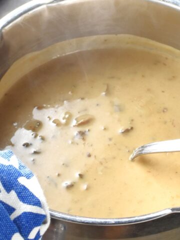 Close-up view of wild mushroom sauce in pot with spoon.