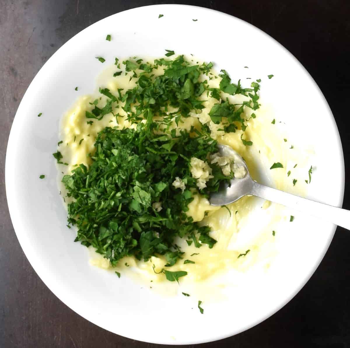 Chopped parsley with butter in white bowl.