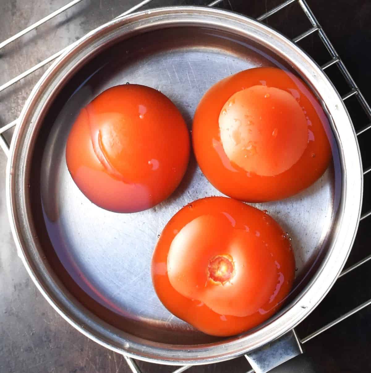 3 tomatoes in pot with water.