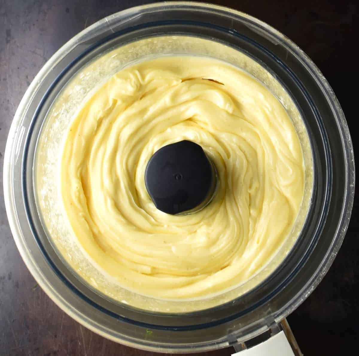 Top down view of homemade mayonnaise in food processor bowl.