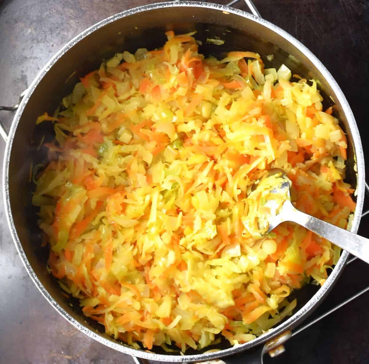 Grated vegetables in pot with spoon.