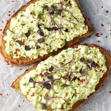 Top down view of 2 sliced of cottage cheese avocado toast with garnish.