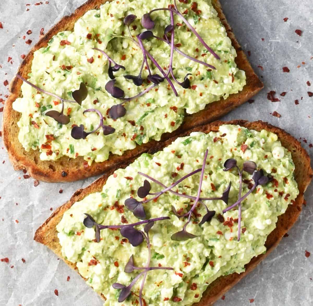 Top down view of 2 sliced of cottage cheese avocado toast with garnish.