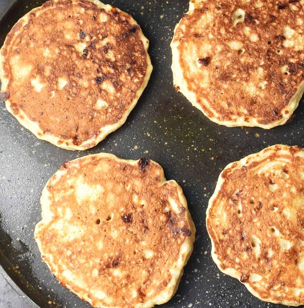 Cooking 4 pancakes in pan.