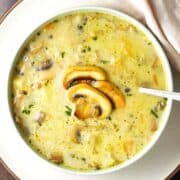 Top down view of Polish mushroom soup in white bowl with spoon.