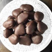 Top down view of chocolate covered prunes in glass bowl.