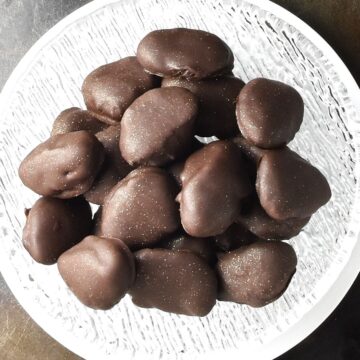 Top down view of chocolate covered prunes in glass bowl.