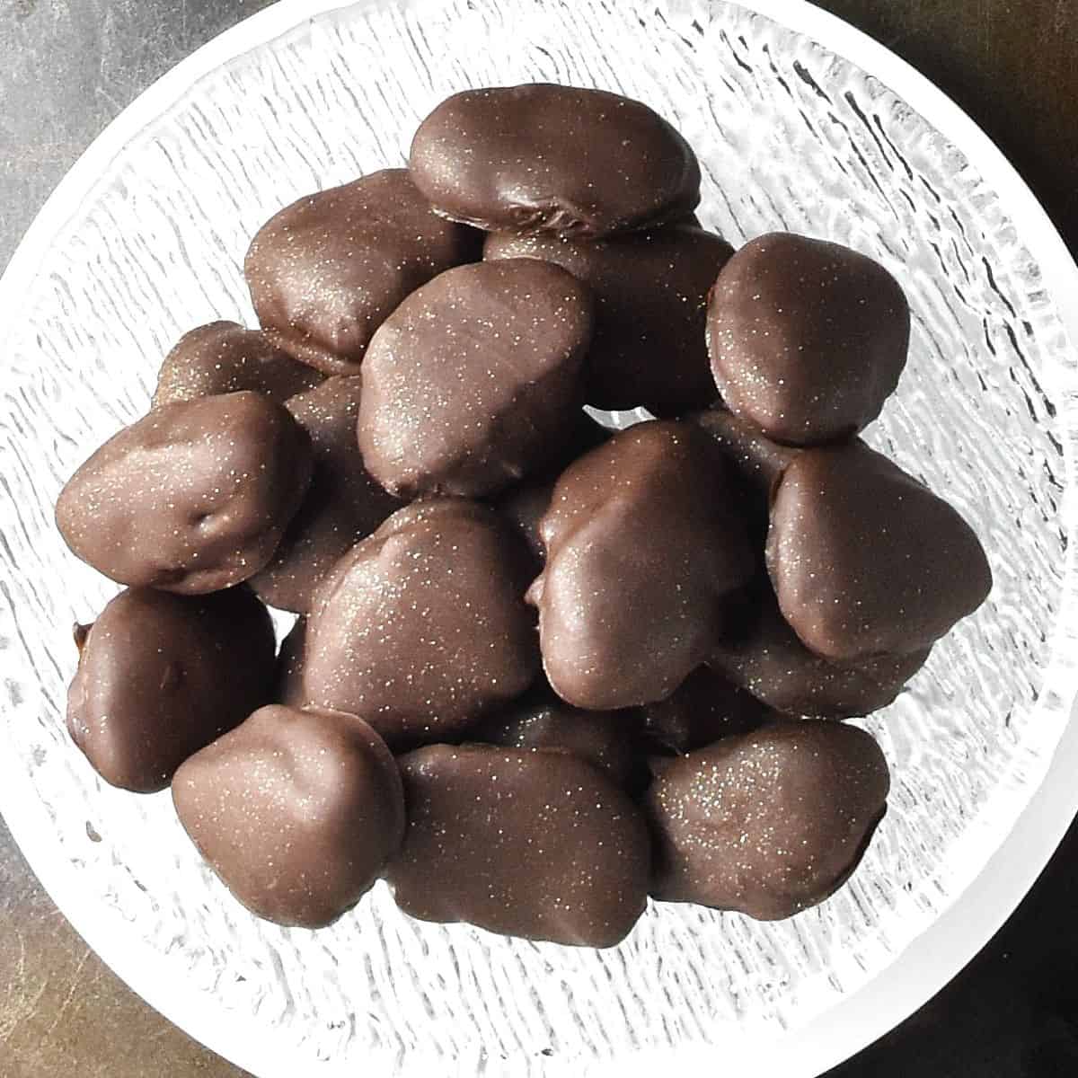Top down view of chocolate covered prunes in glass bowl.