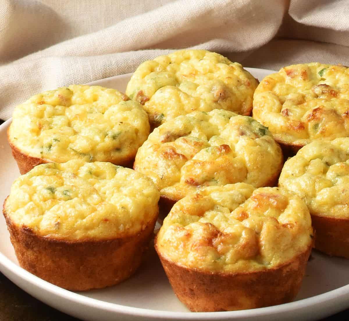 Side view of baked potato and egg muffins with golden tops on pink plate.