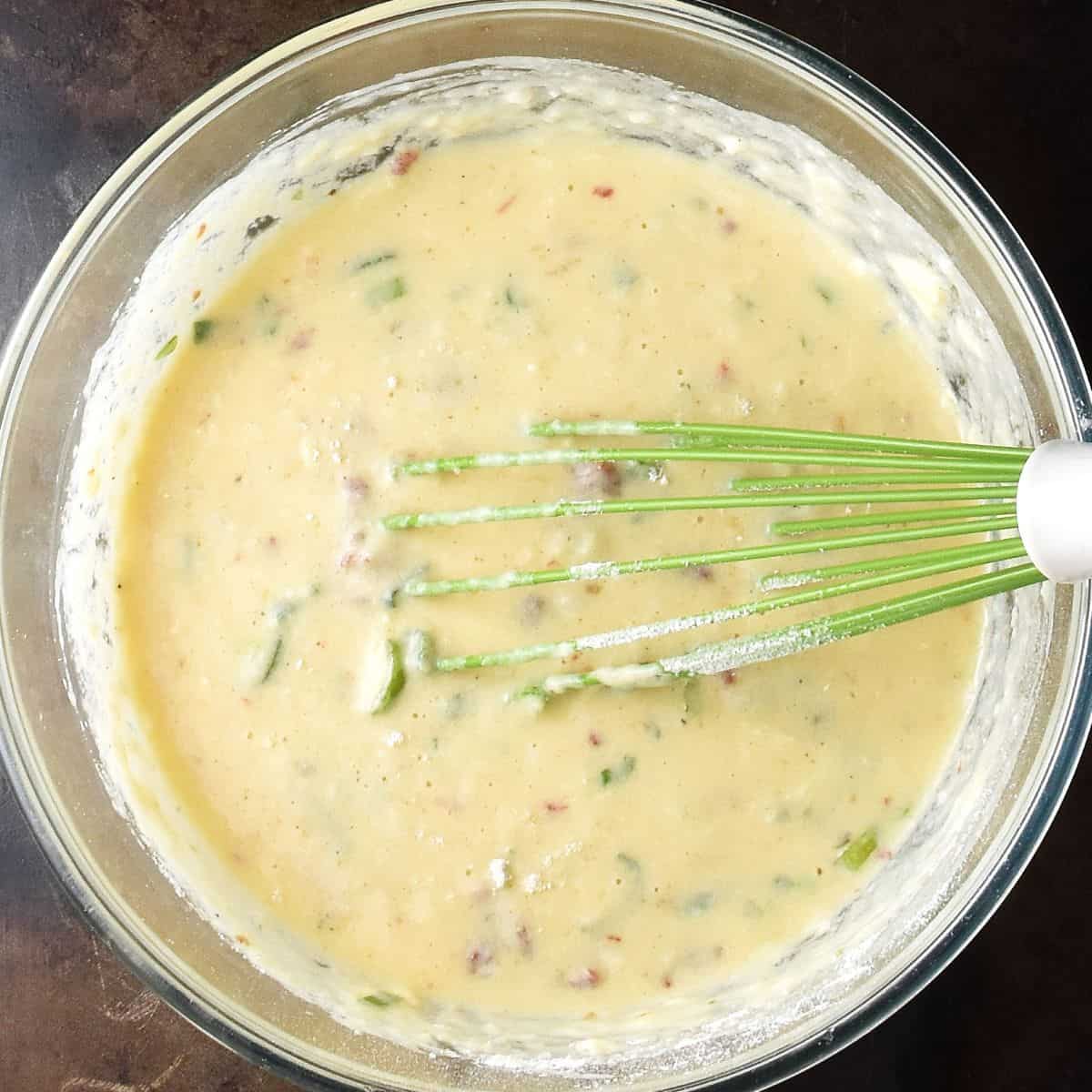 Potato egg muffin batter in large glass bowl with whisk.