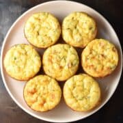 Top down view of 7 potato egg muffins on pink plate.