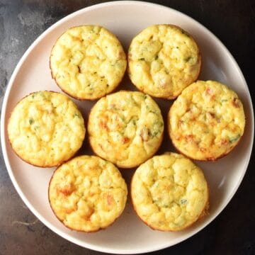Top down view of 7 potato egg muffins on pink plate.
