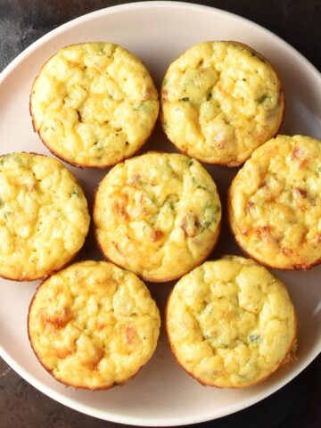 Top down view of 7 potato egg muffins on pink plate.