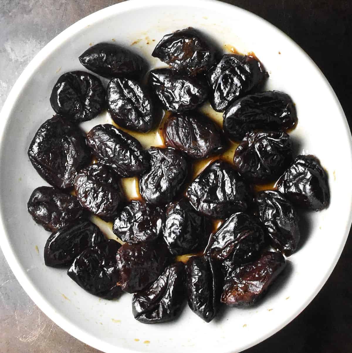 Alcohol infused prunes in white bowl.